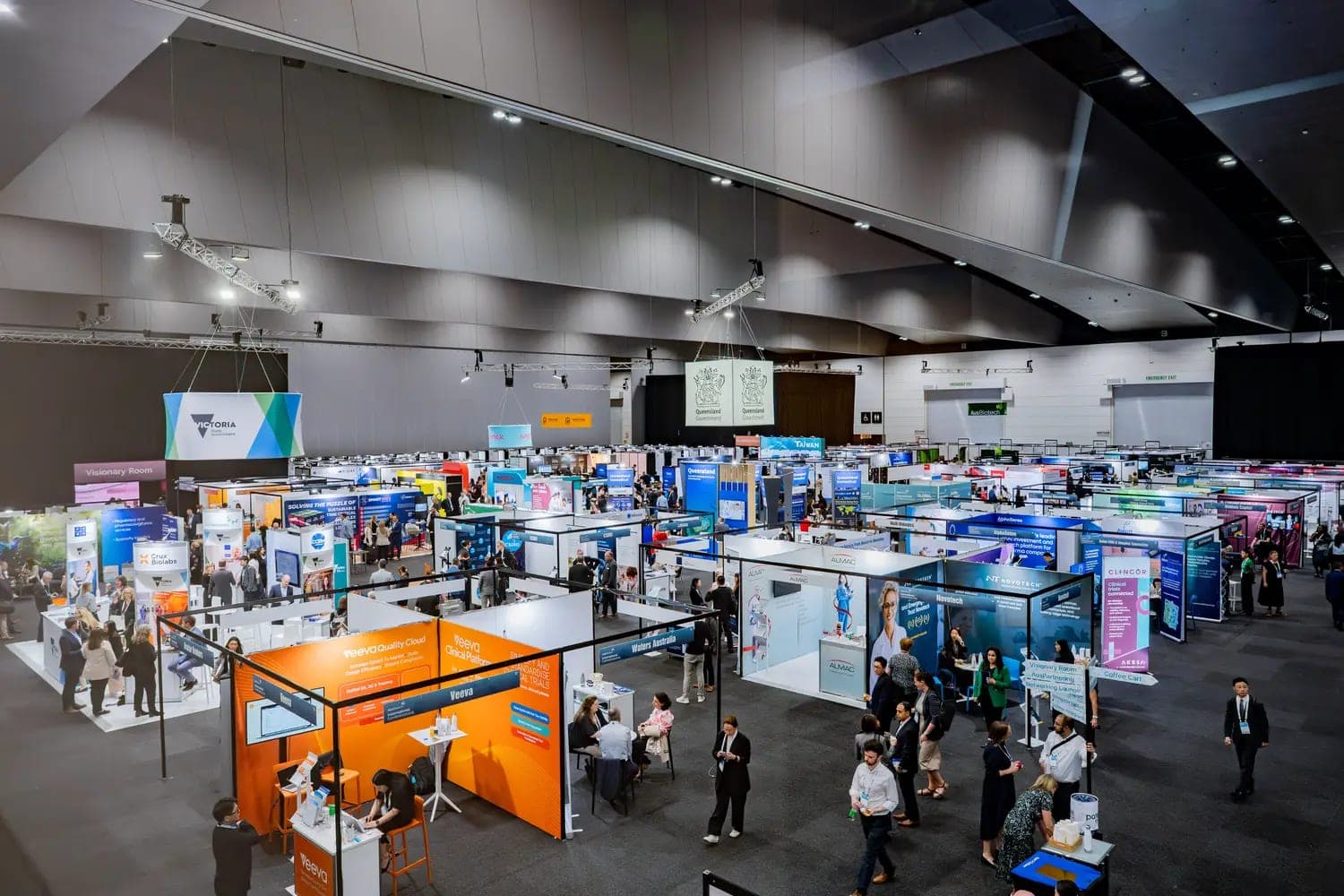An overhead view of a busy exhibition hall with dozens of exhibitor booths